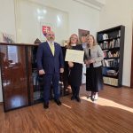 foto interiér, traja ludia, v strede p. Vuksic drzí poverenie